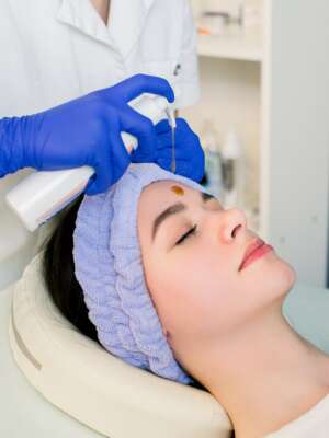 Beautiful Face Skin. Cosmetologist doing beauty procedure for patient. Face massage, skincare. Woman